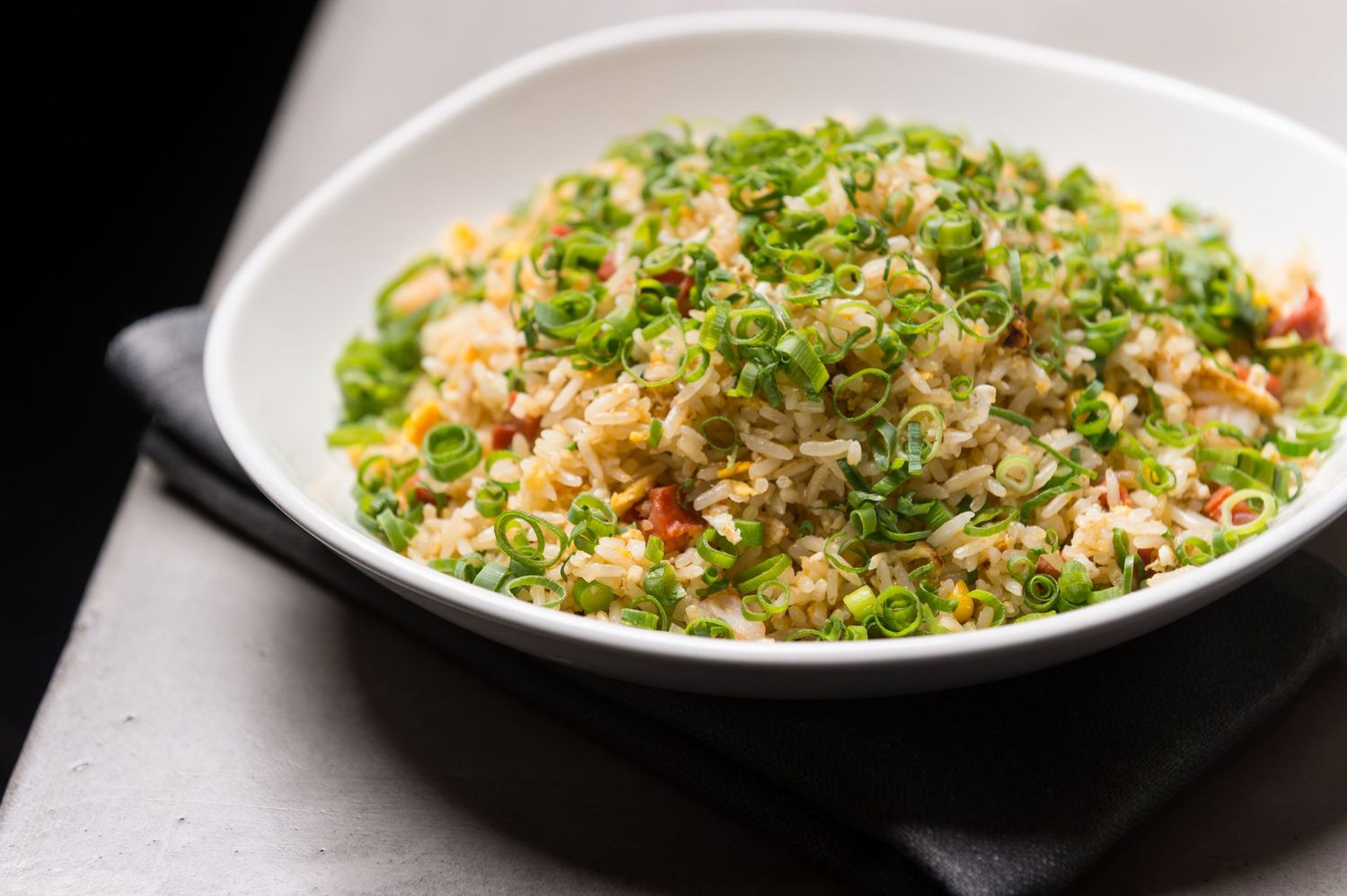 Fresh quinoa salad topped with herbs and vegetables served in a white bowl.