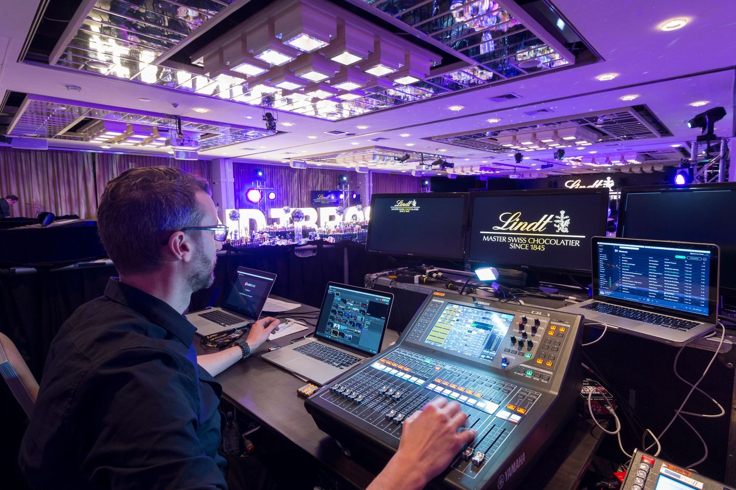 Professional audio mixing console with purple lighting in a recording studio control room.