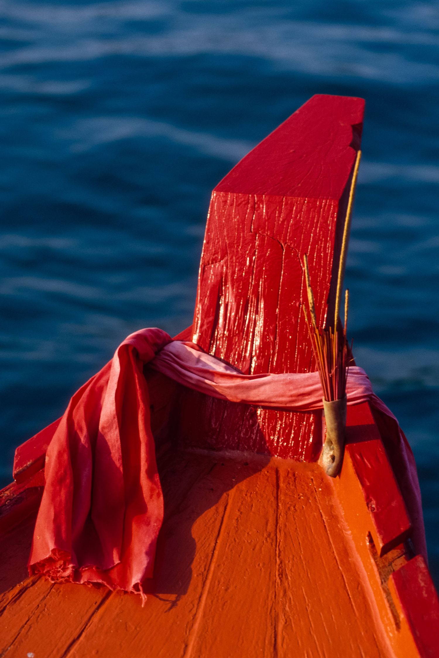 Close-up of a weathered red life preserver or buoy against deep blue water.