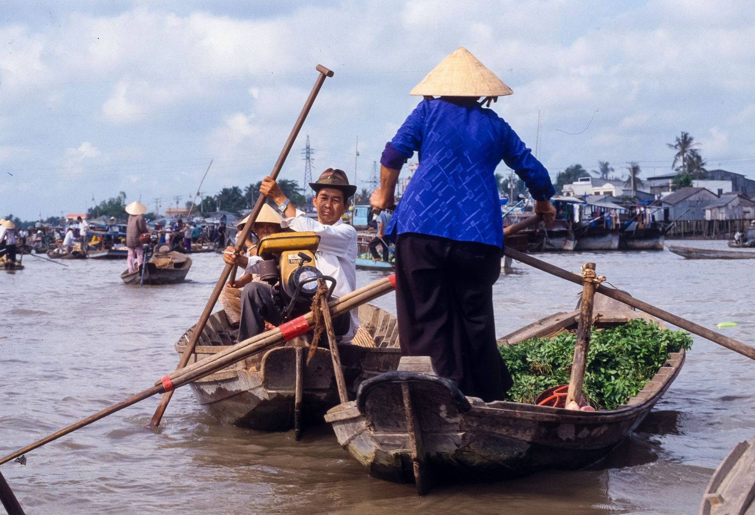 Wooden boats carrying passengers and goods across busy river delta waterway.