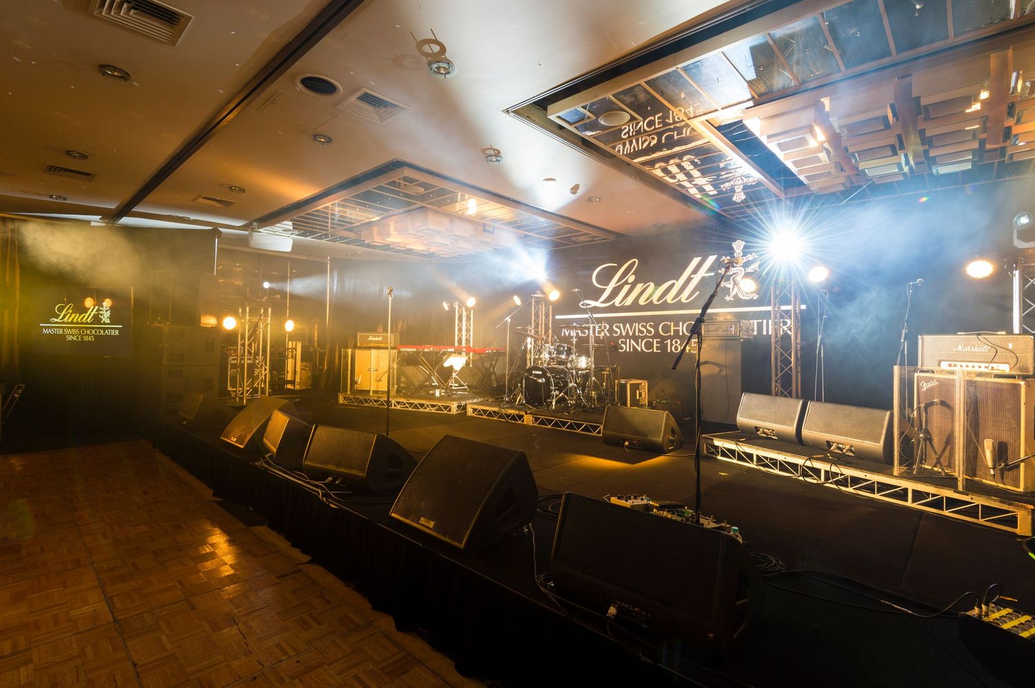 A dimly lit indoor venue with atmospheric fog and dramatic lighting creating a moody ambiance.