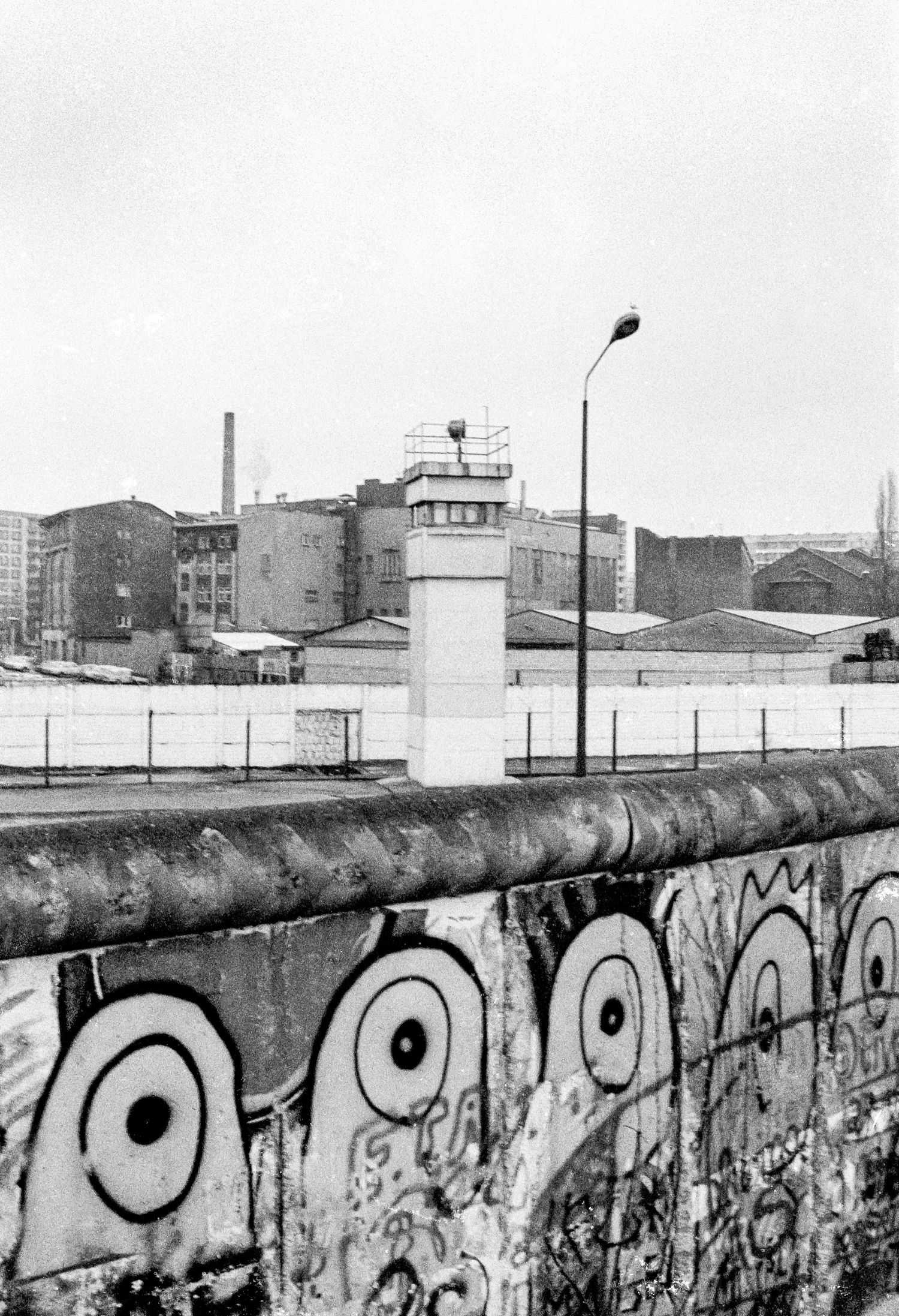 Graffiti-covered section of the Berlin Wall stretching across an urban landscape.