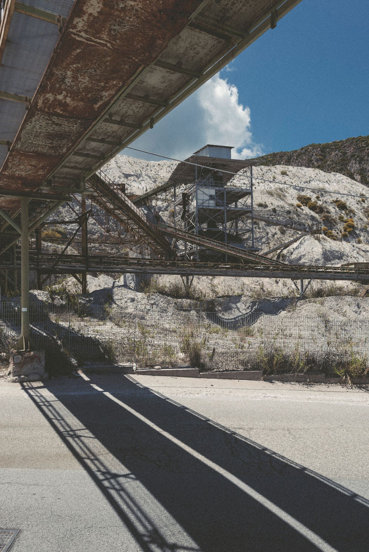 Panoramic view of a snow-covered quarry with industrial conveyor belt structures casting shadows on the ground below.