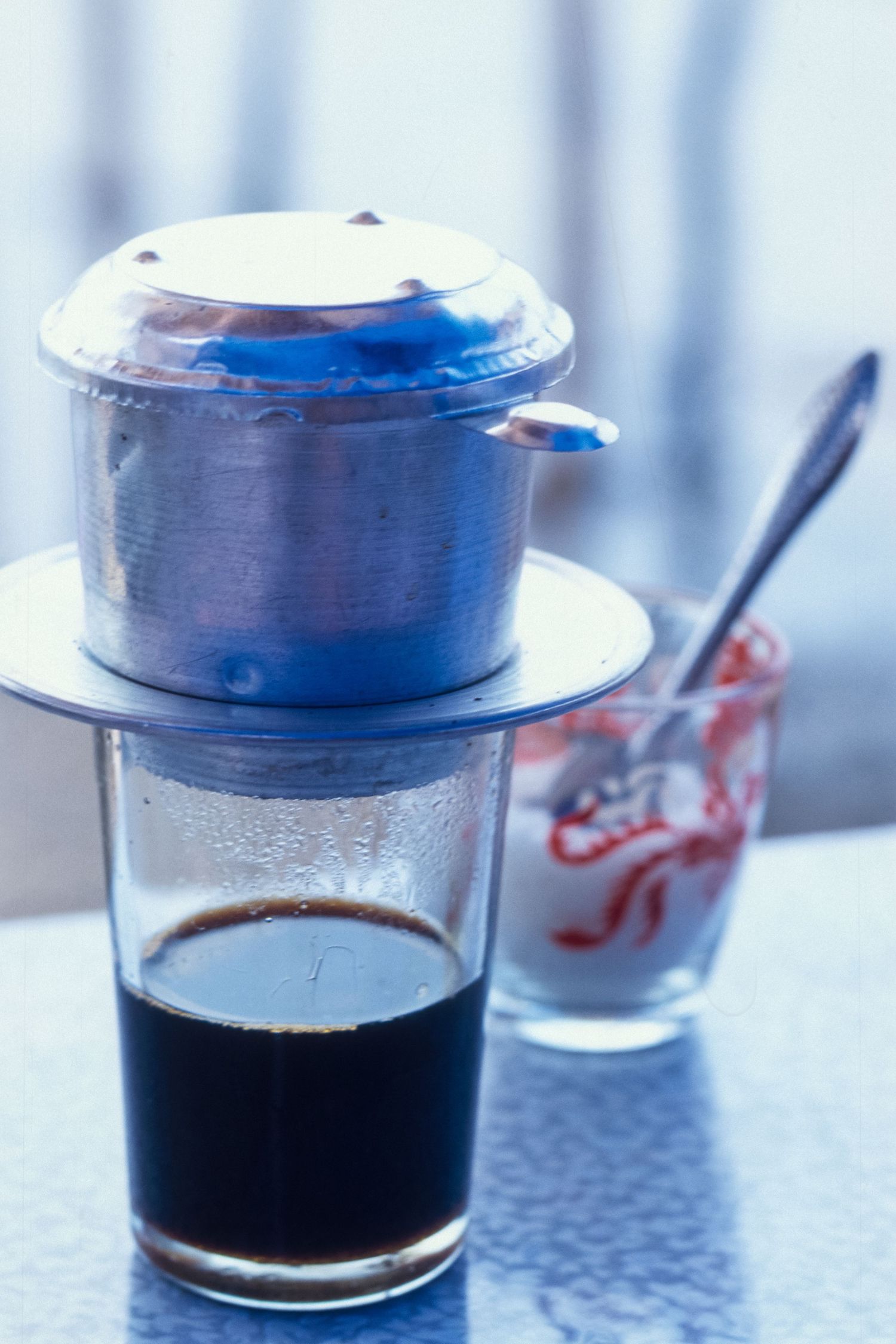 Clear glass cups containing dark liquid on a light colored surface.