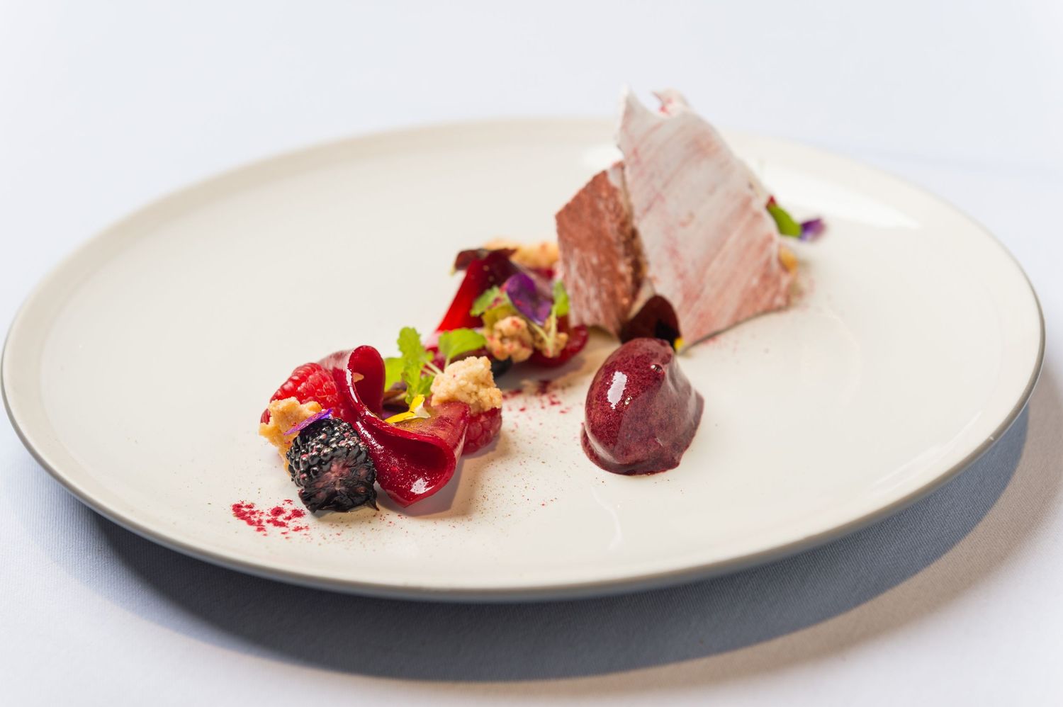 Series of sophisticated meat dishes with colorful garnishes served on pristine white plates.