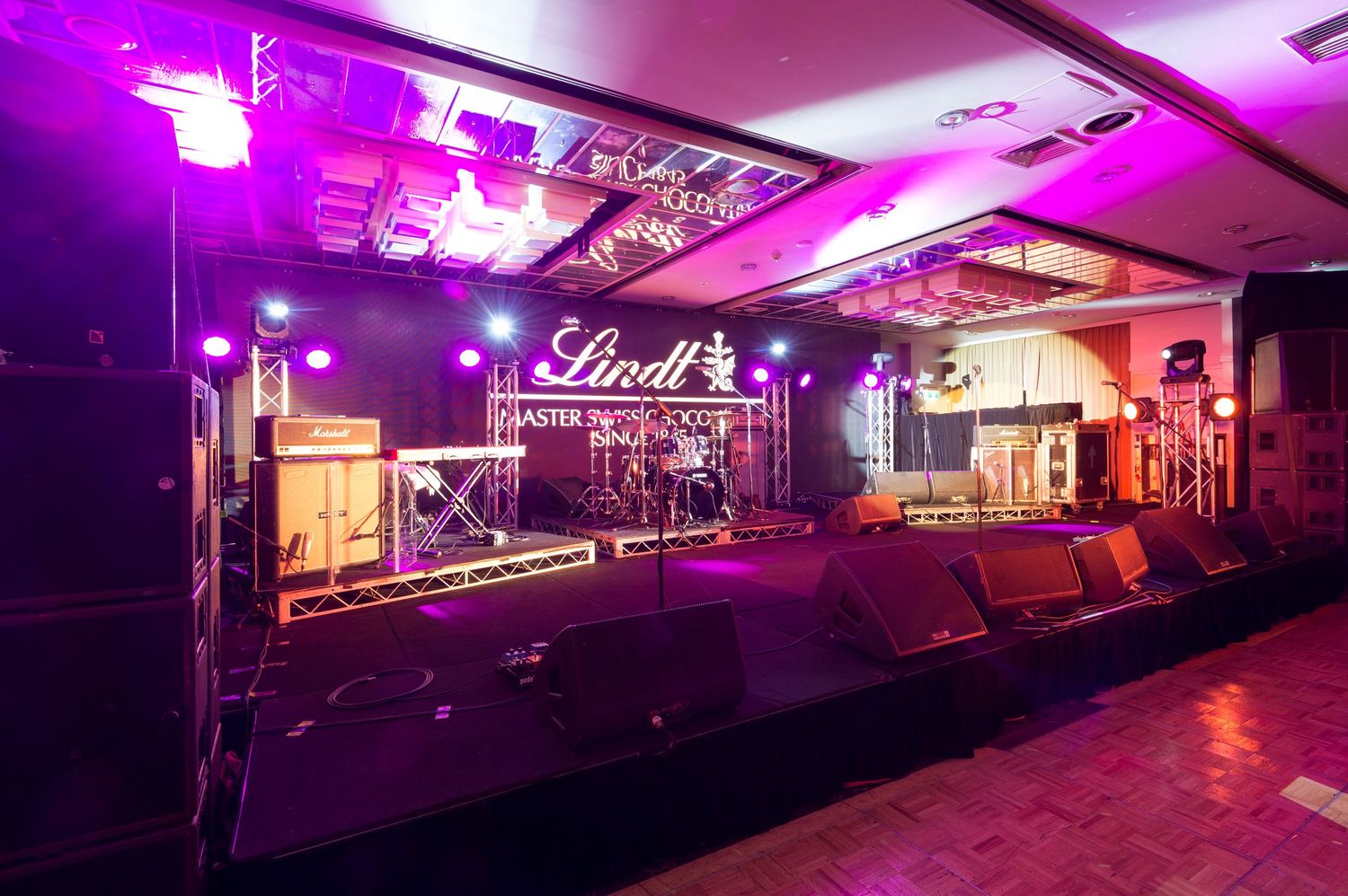 Nightclub interior with purple and pink LED lighting illuminating multiple rooms and hallways in a moody atmosphere.