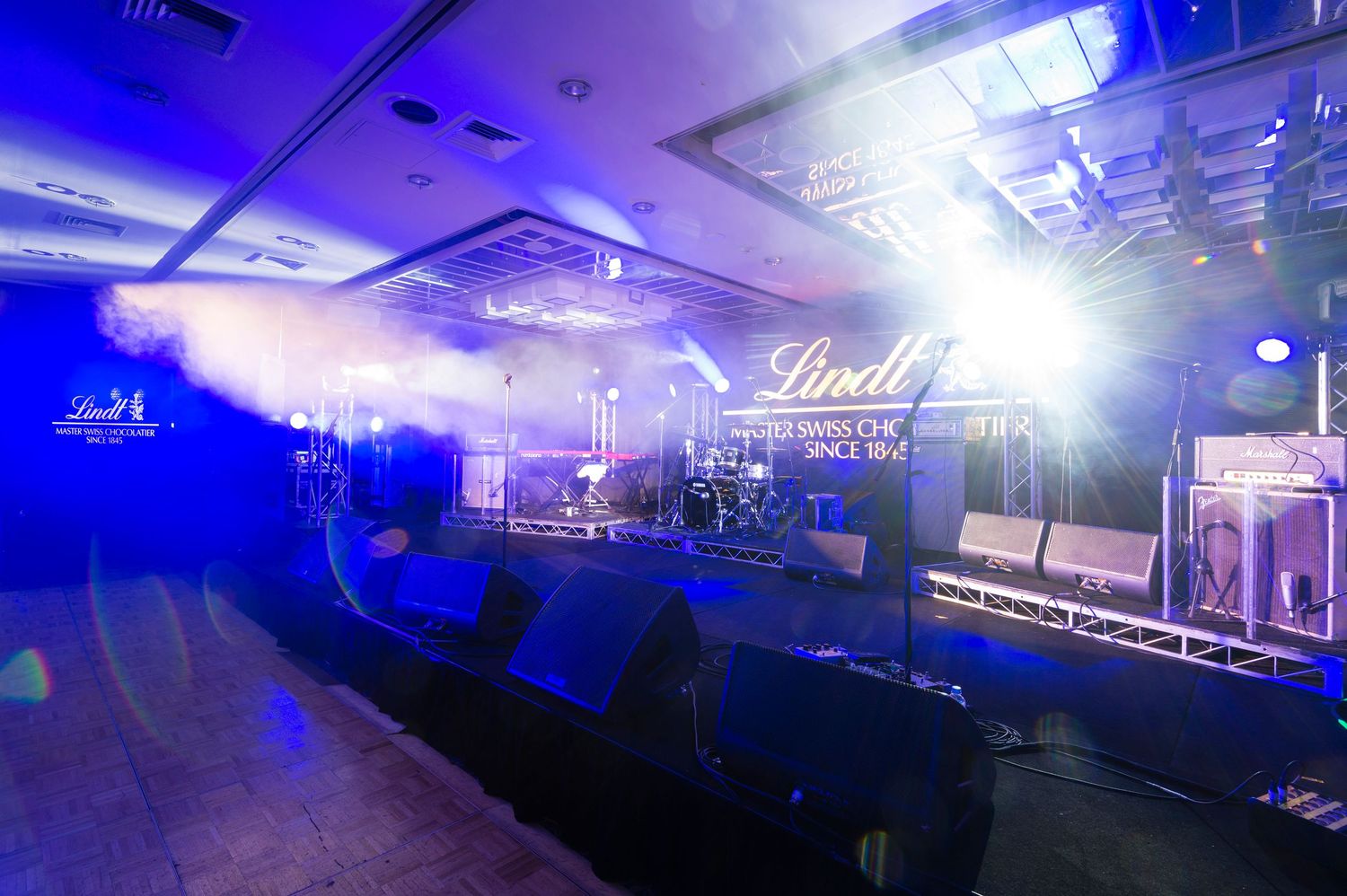 Concert venue illuminated in dramatic blue lighting with fog effects creating an atmospheric performance space.