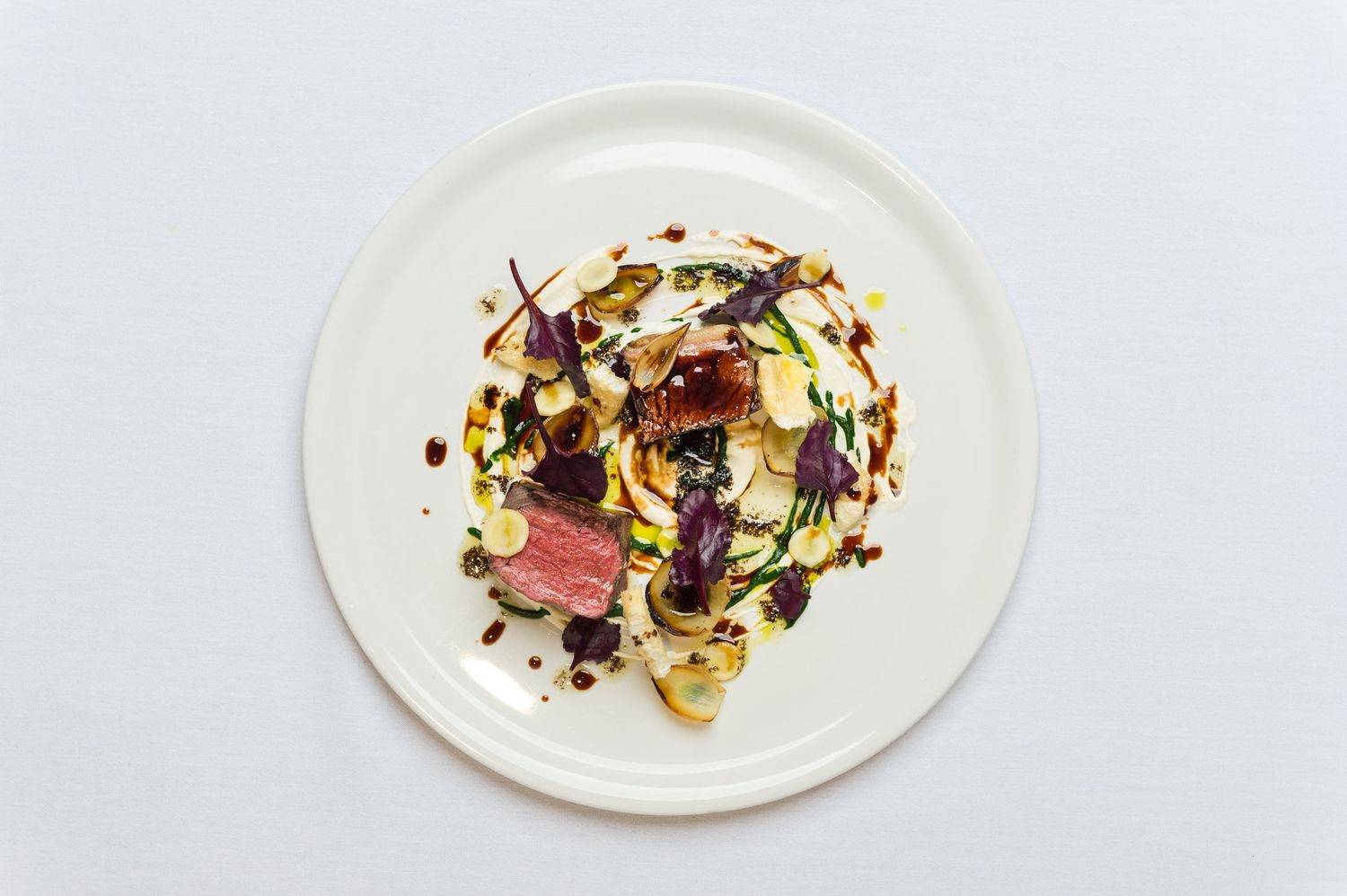 Collection of modern plated dishes featuring meat and vegetables on white dinnerware.