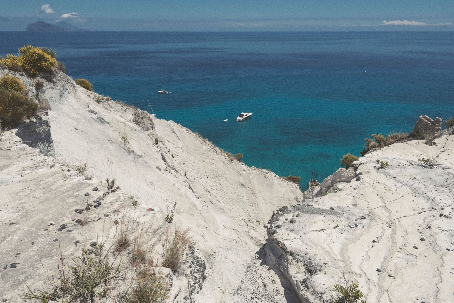 Panoramic view of white limestone cliffs overlooking crystal clear turquoise Mediterranean waters on a sunny day.