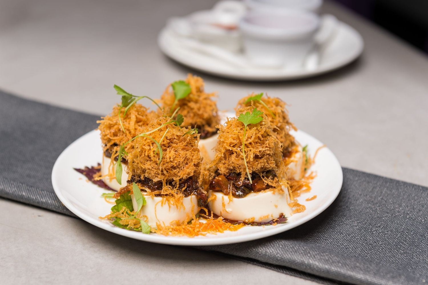 Crispy breaded seafood dish garnished with microgreens on white plate.