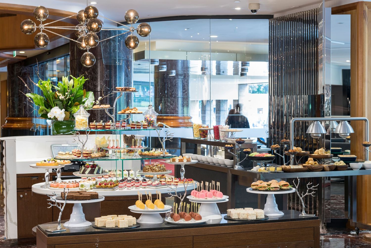 Extensive buffet spread featuring various pastries and desserts displayed on raised white platforms.