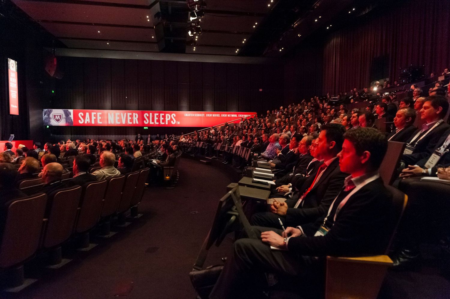 Large audience seated in a dimly lit auditorium during a technology conference presentation at Sydney ICC.