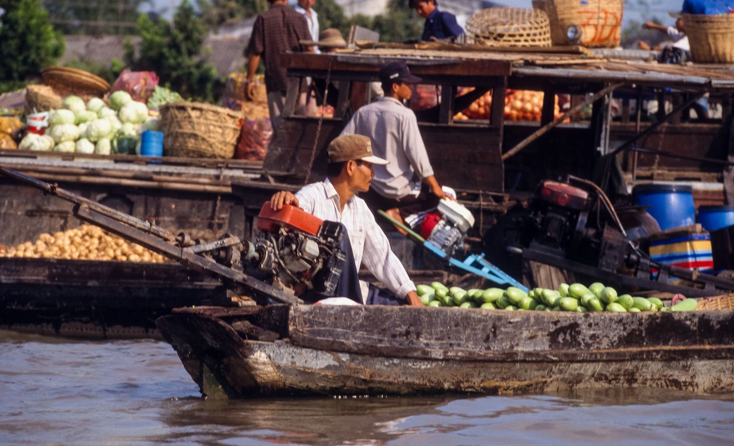 Traditional floating market with wooden boats selling fresh produce and goods.