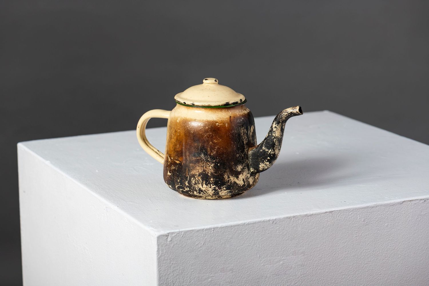 Ceramic teapots and cups arranged on white display pedestals against a dark gray background.