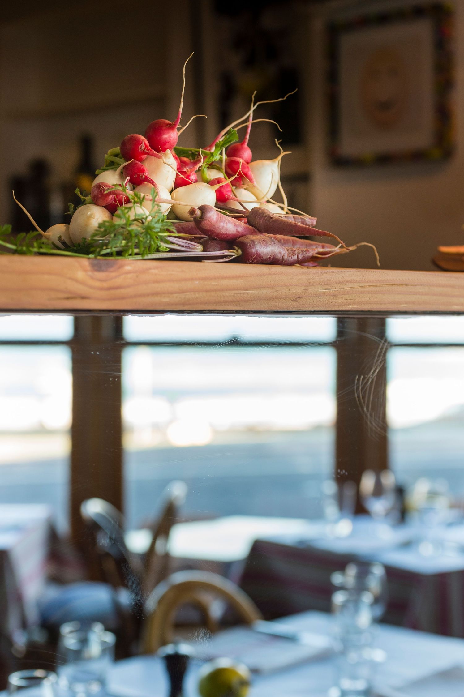 Fresh red radishes arranged on a wooden surface in a restaurant setting.