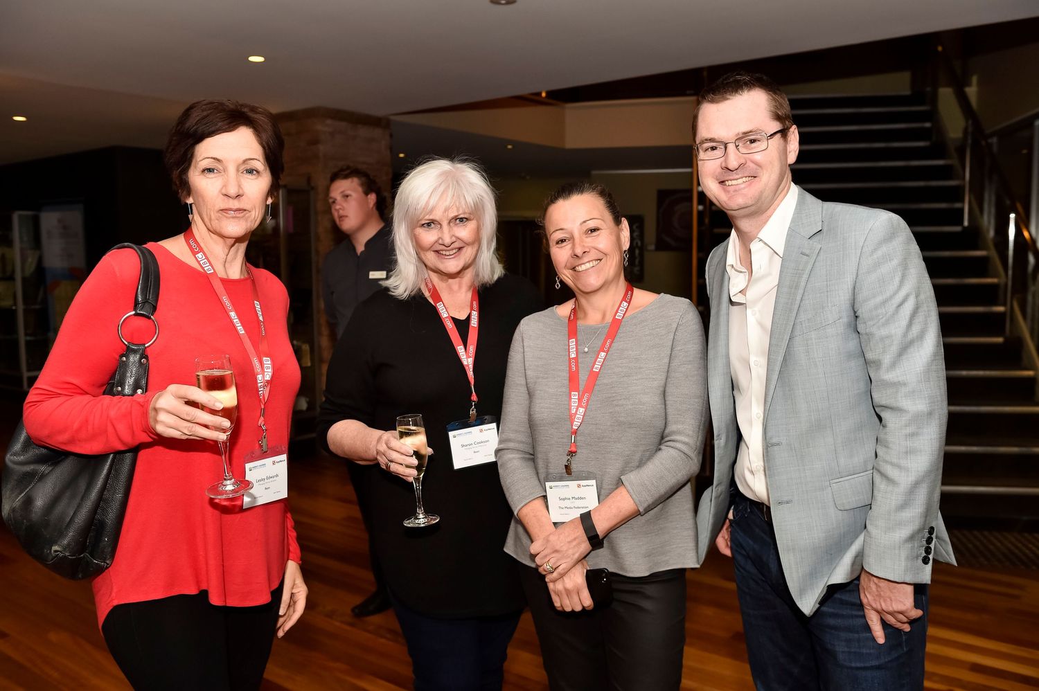Professionals in business attire networking at an indoor corporate reception.