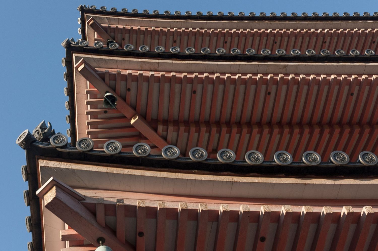 Traditional Japanese temple roofline with ornate terracotta tiles and decorative ridge details.