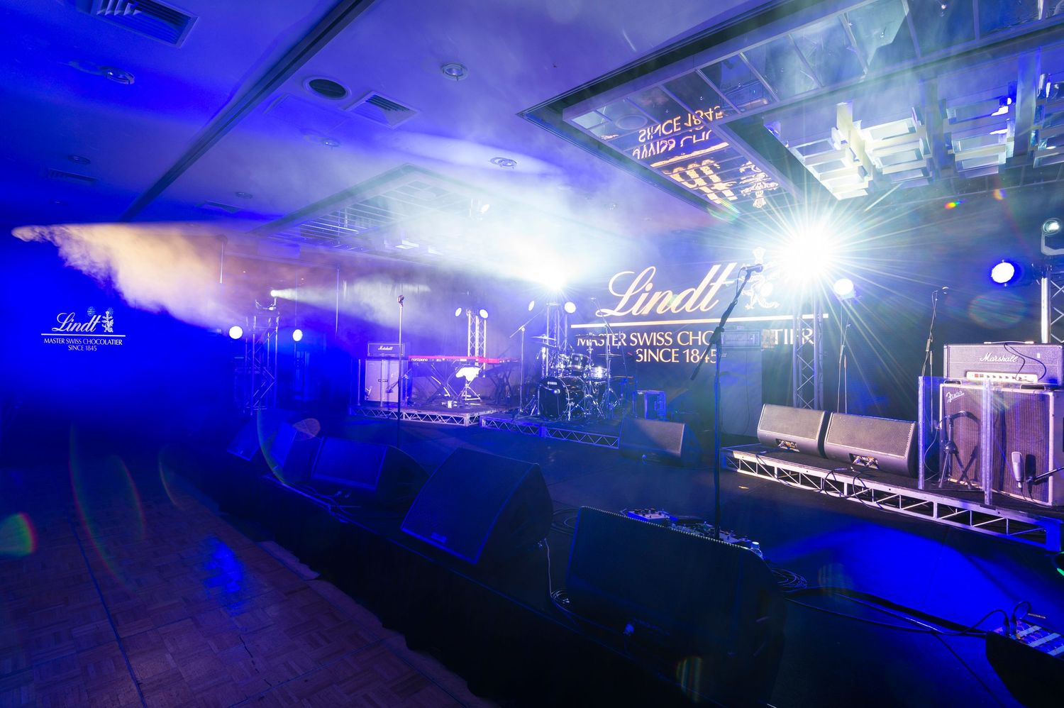 Concert stage illuminated with dramatic blue lighting and fog effects creating an atmospheric performance environment.