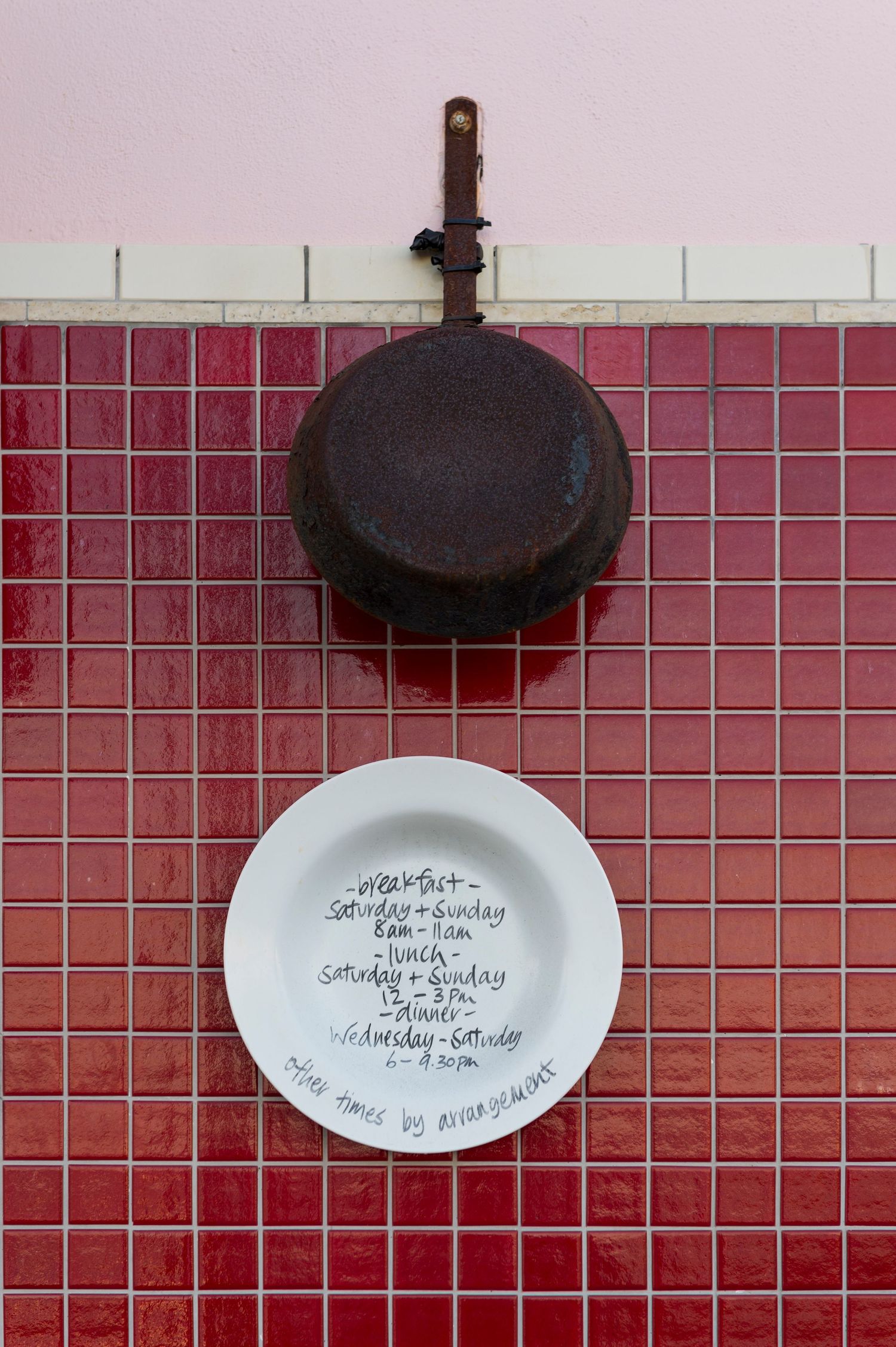 Pink tiled wall with decorative ceramic plates mounted as wall art.