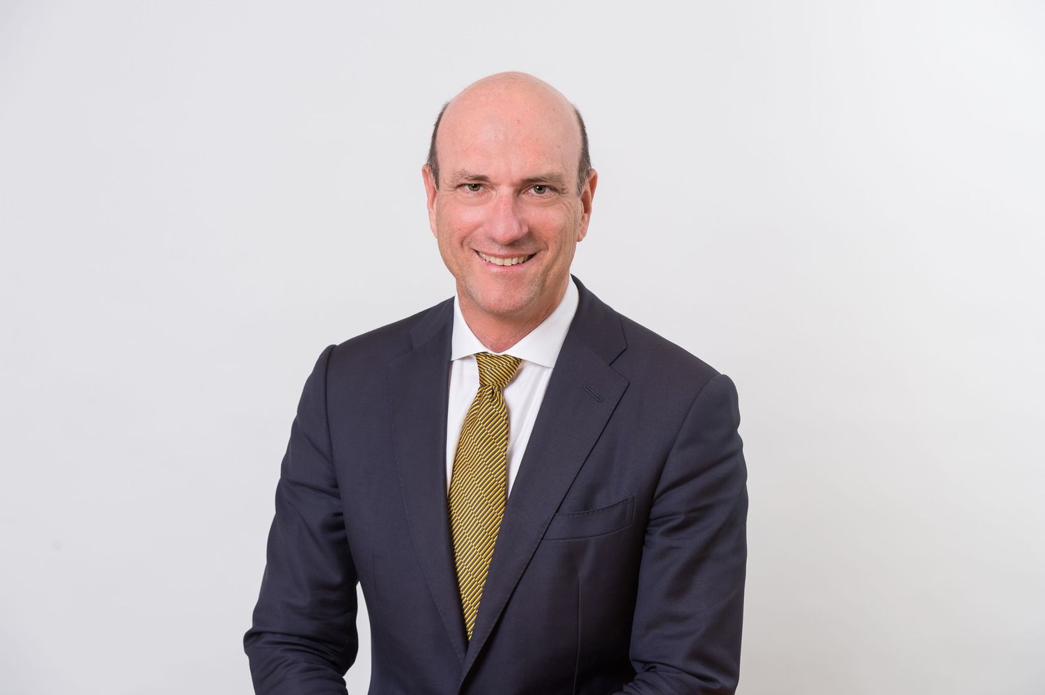 Business portraits showing person in dark suit with yellow tie.