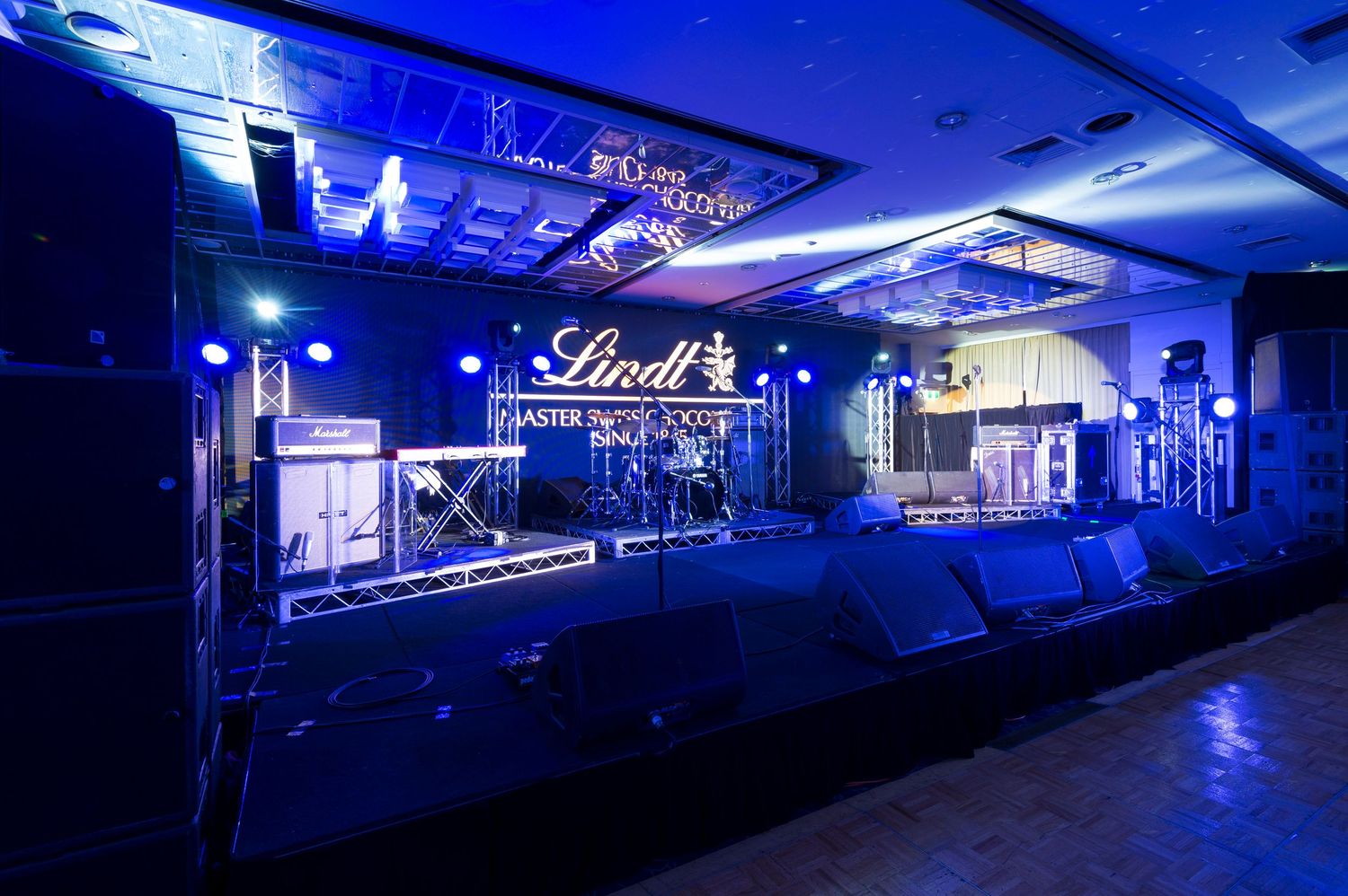 A series of nighttime photos showing a dimly lit commercial space illuminated in deep blue lighting and neon signage.