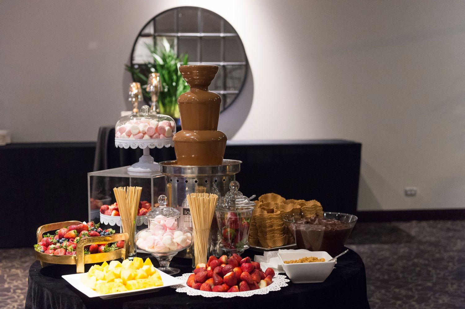 A party buffet table with snacks, fresh fruit, desserts and drinks spread out for guests to enjoy.