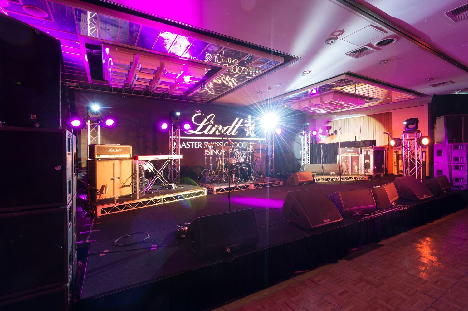 A dark nightclub interior illuminated with vibrant purple and pink LED lighting along the walls and ceiling.