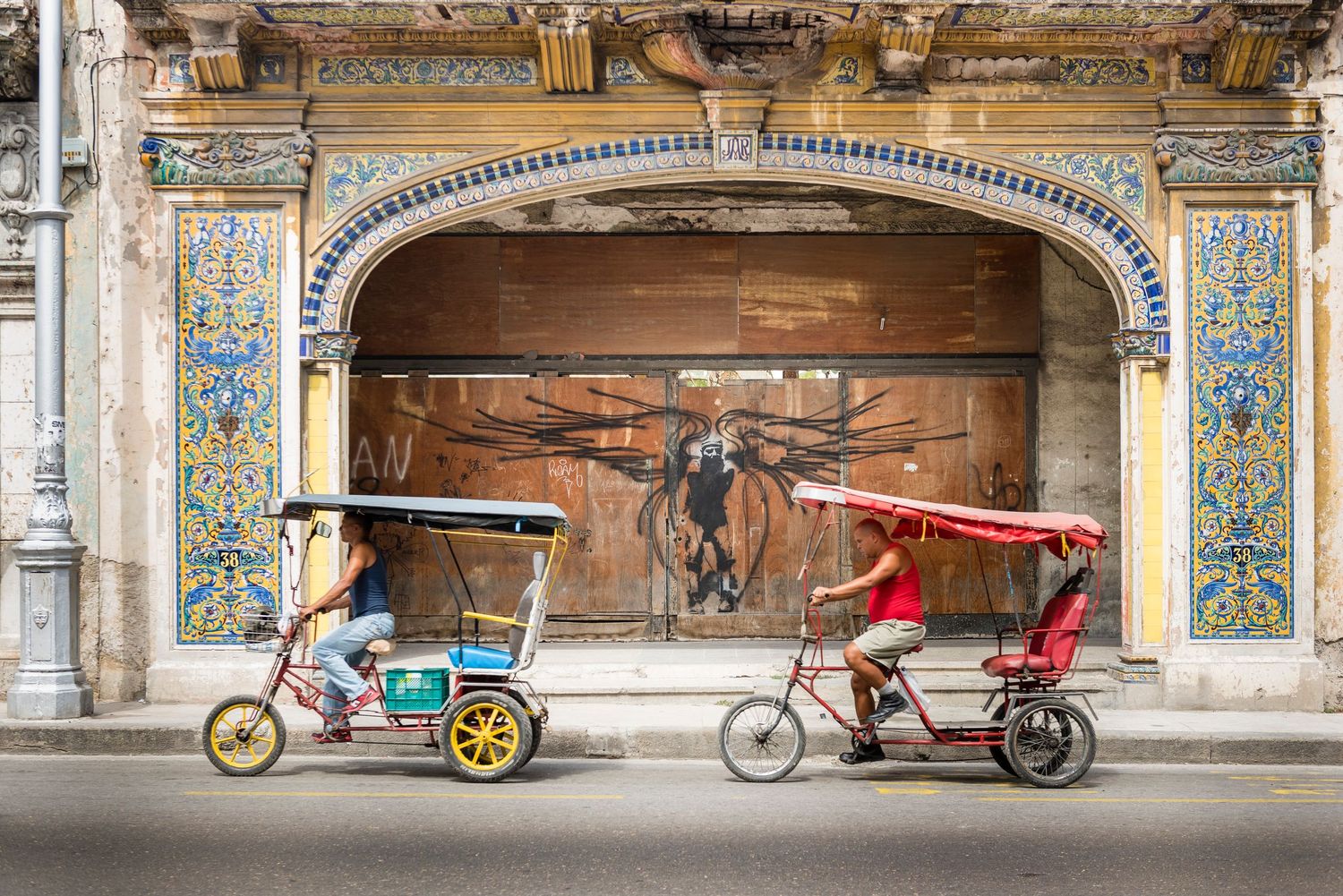 Ornate colonial architecture with decorated arches and parked rickshaws in foreground.