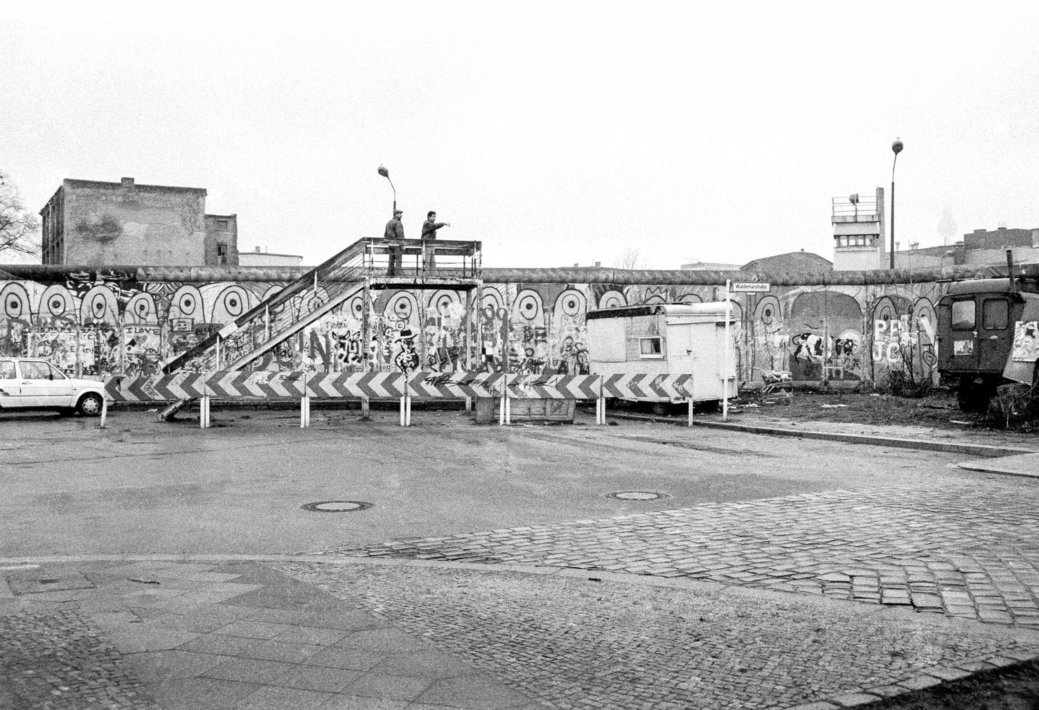 Wide view of the Berlin Wall death strip with guard towers and barricades.