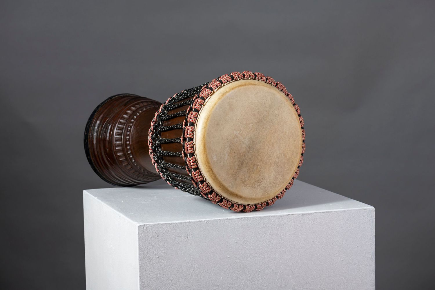 Wooden drums or percussion instruments displayed on white platforms with dramatic lighting.