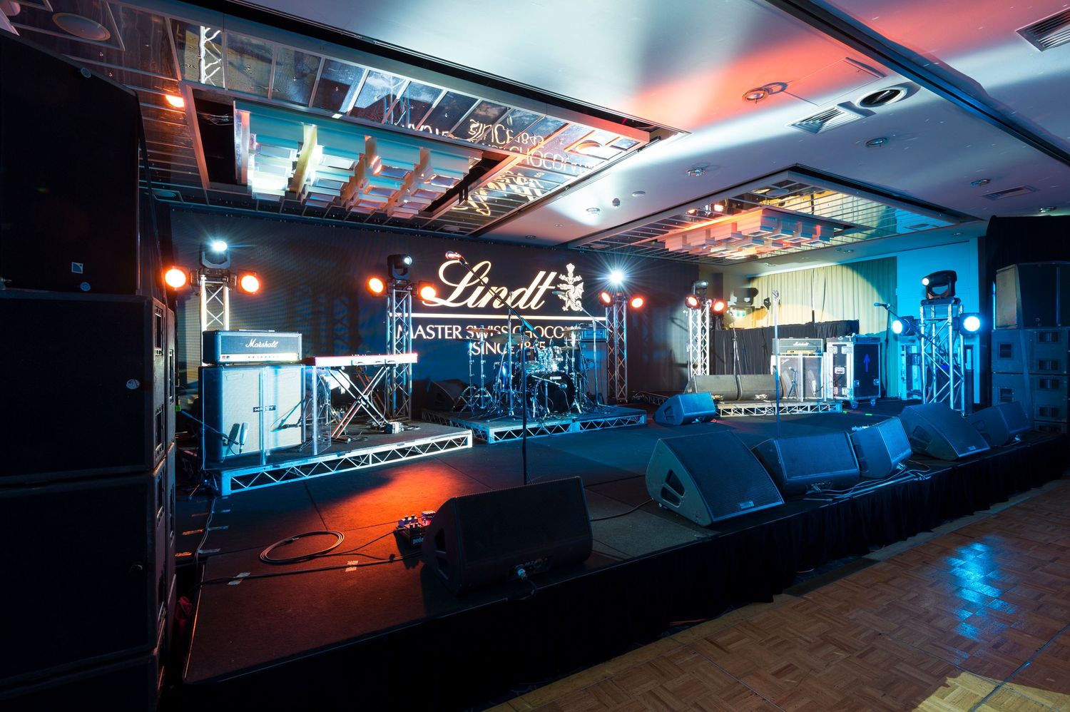 Styled room set up of sponsored event with staging multiple lighting creating a moody atmospheric ambiance.