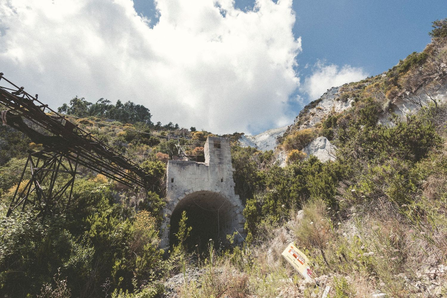 A scenic mountain landscape with cascading waterfalls and lush greenery surrounded by rocky cliffs under cloudy skies.