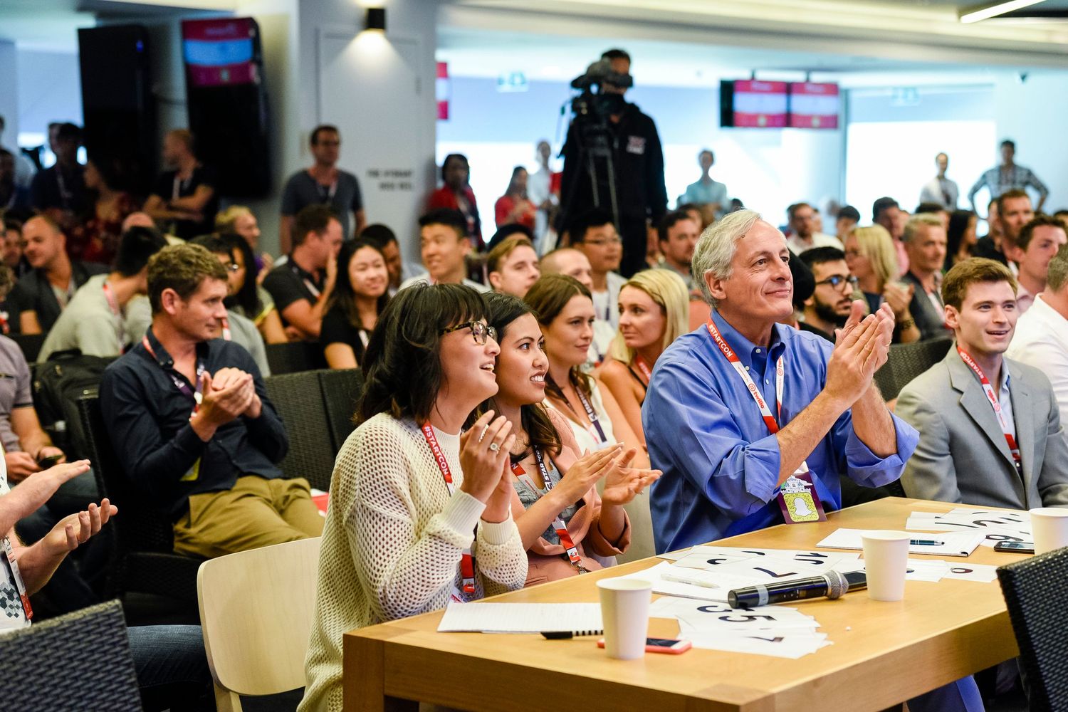 Enthusiastic audience members applaud during a conference presentation at Sydney Royal Randwick.