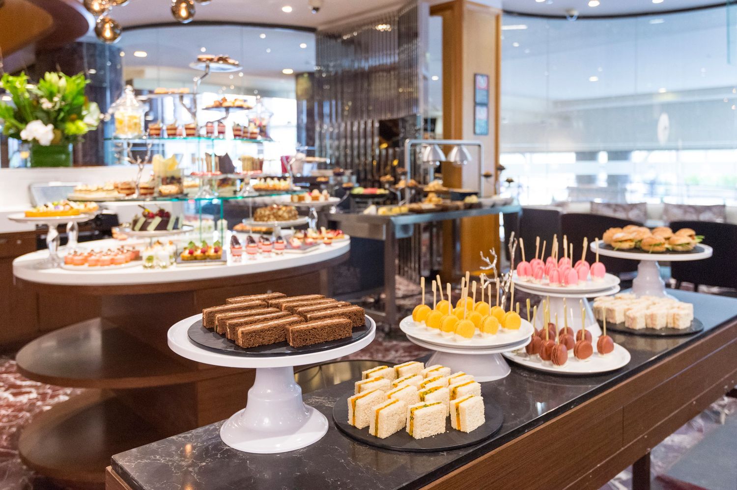 Gourmet dessert buffet with assorted cakes and pastries arranged on tiered serving platters.