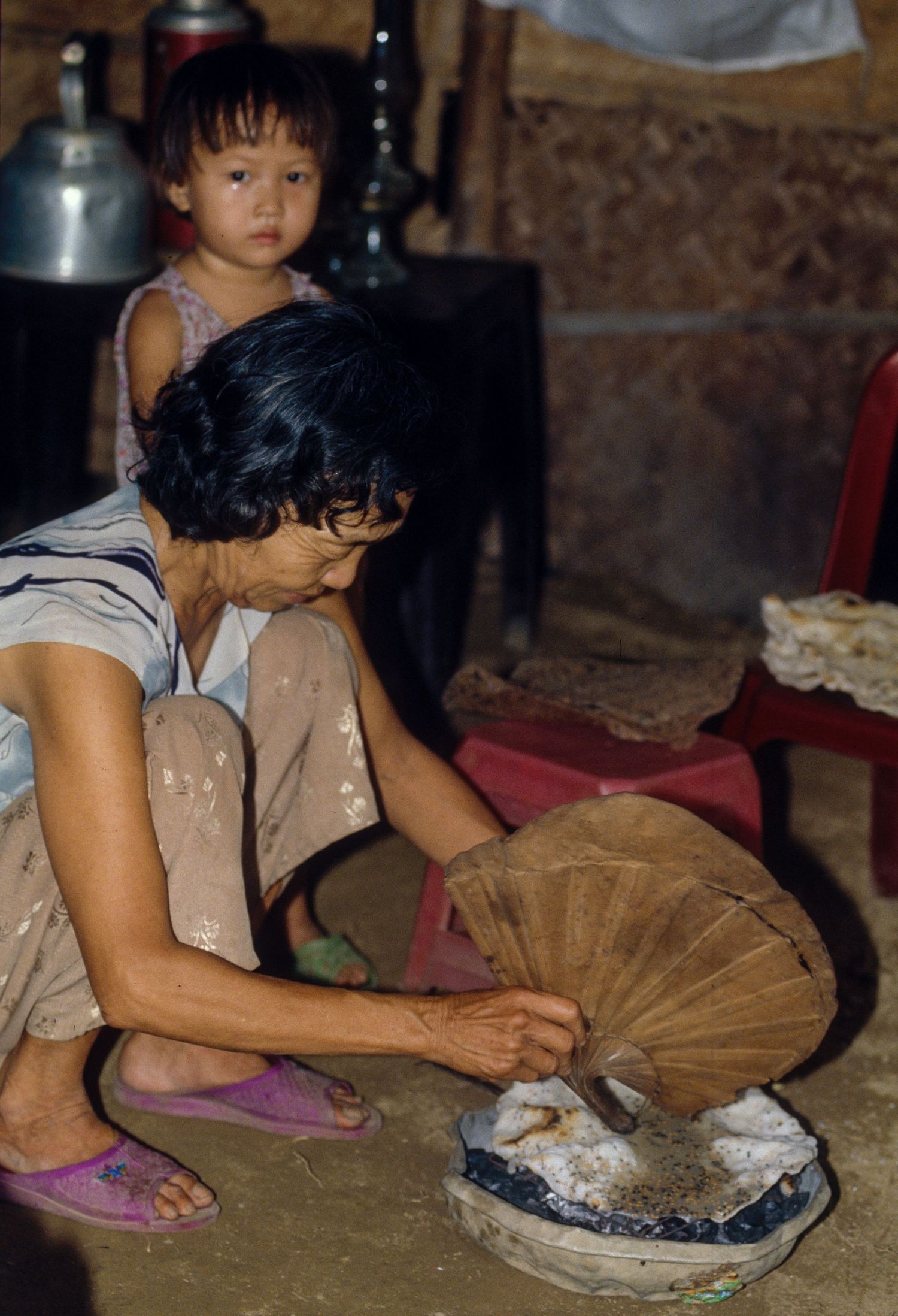 Traditional rice paper making process being demonstrated on a round bamboo tray.