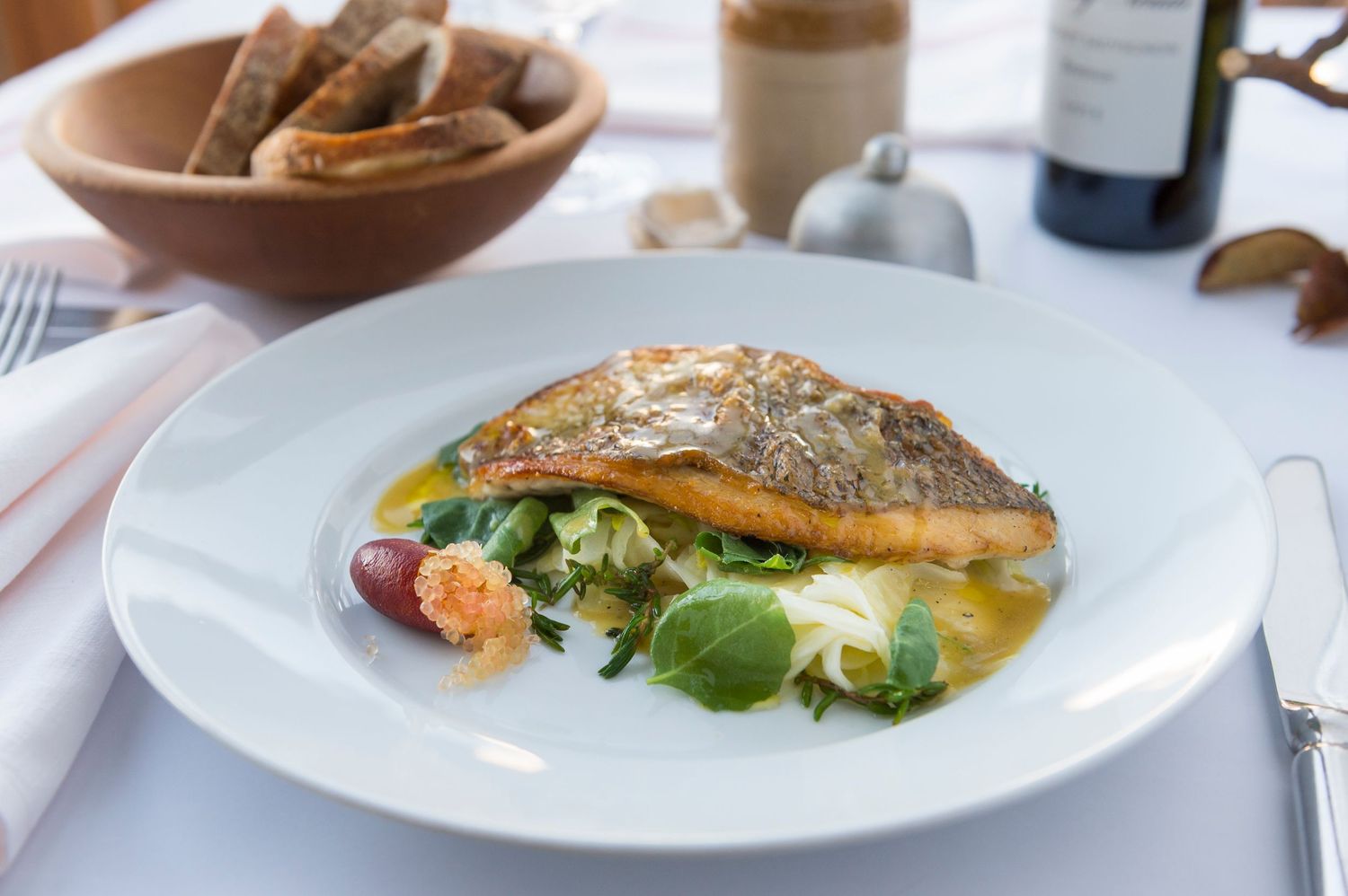 Pan-seared fish fillet served with fresh vegetables on white plate.