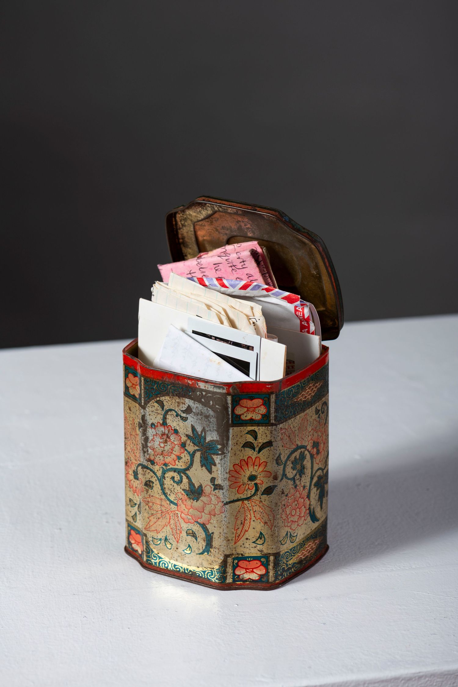 Vintage floral patterned storage box with decorative designs shown from different angles on a light gray surface.