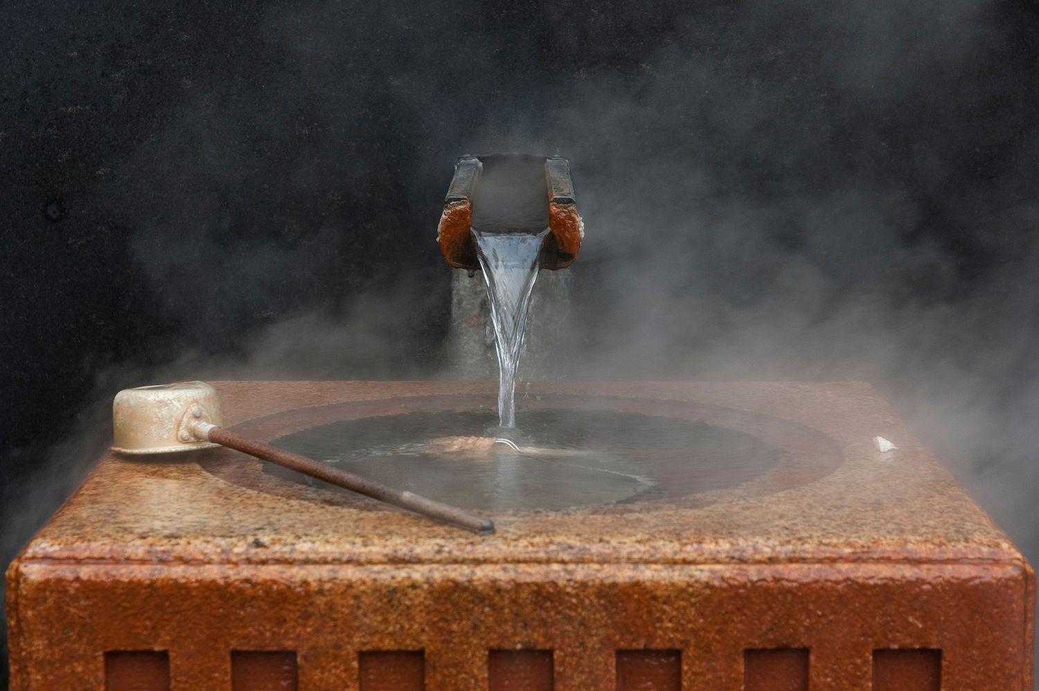 Steam rising from a hot spring or onsen bath with wooden elements in the background.