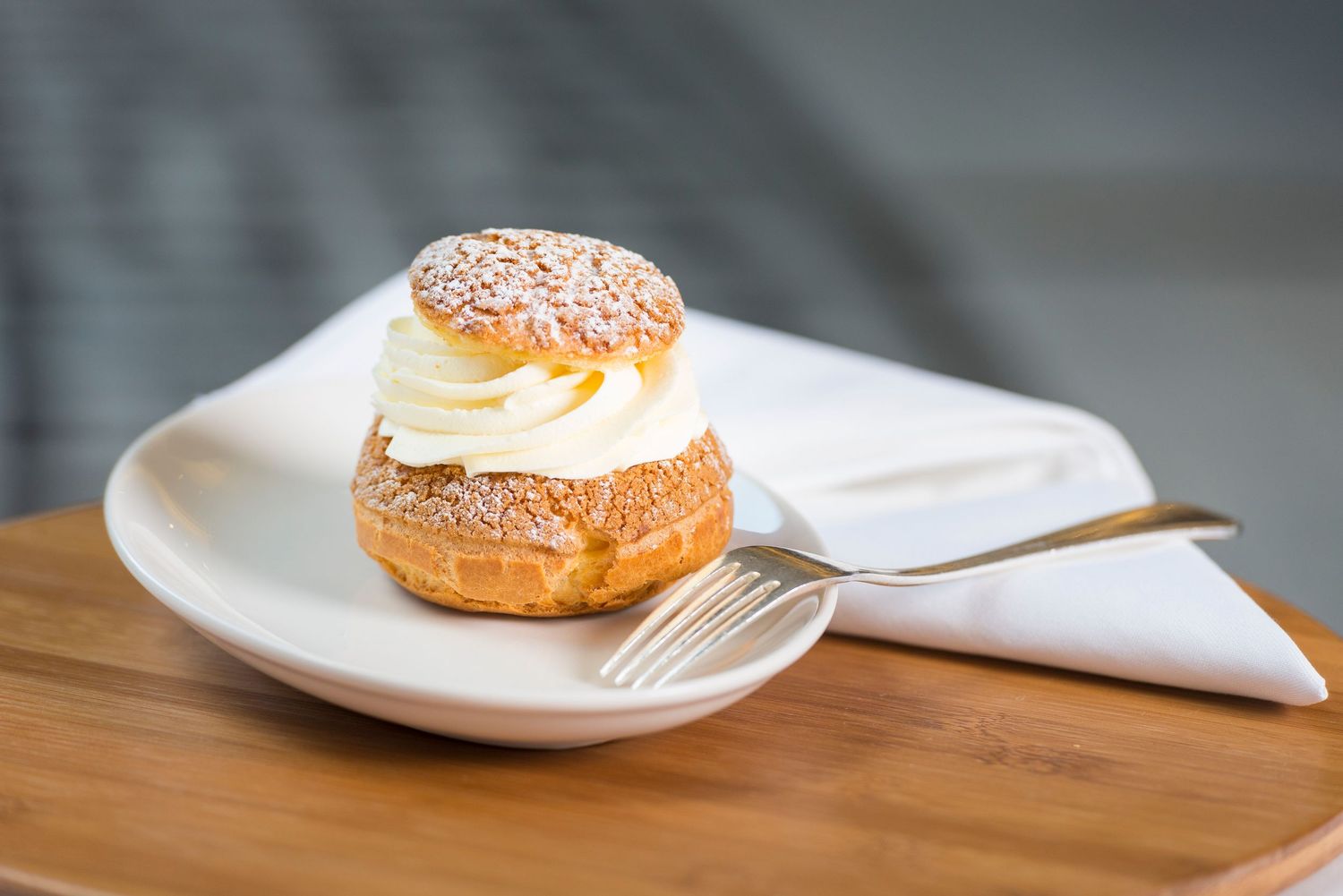 Cream-filled pastry with powdered sugar dusting served on wooden and white plates.