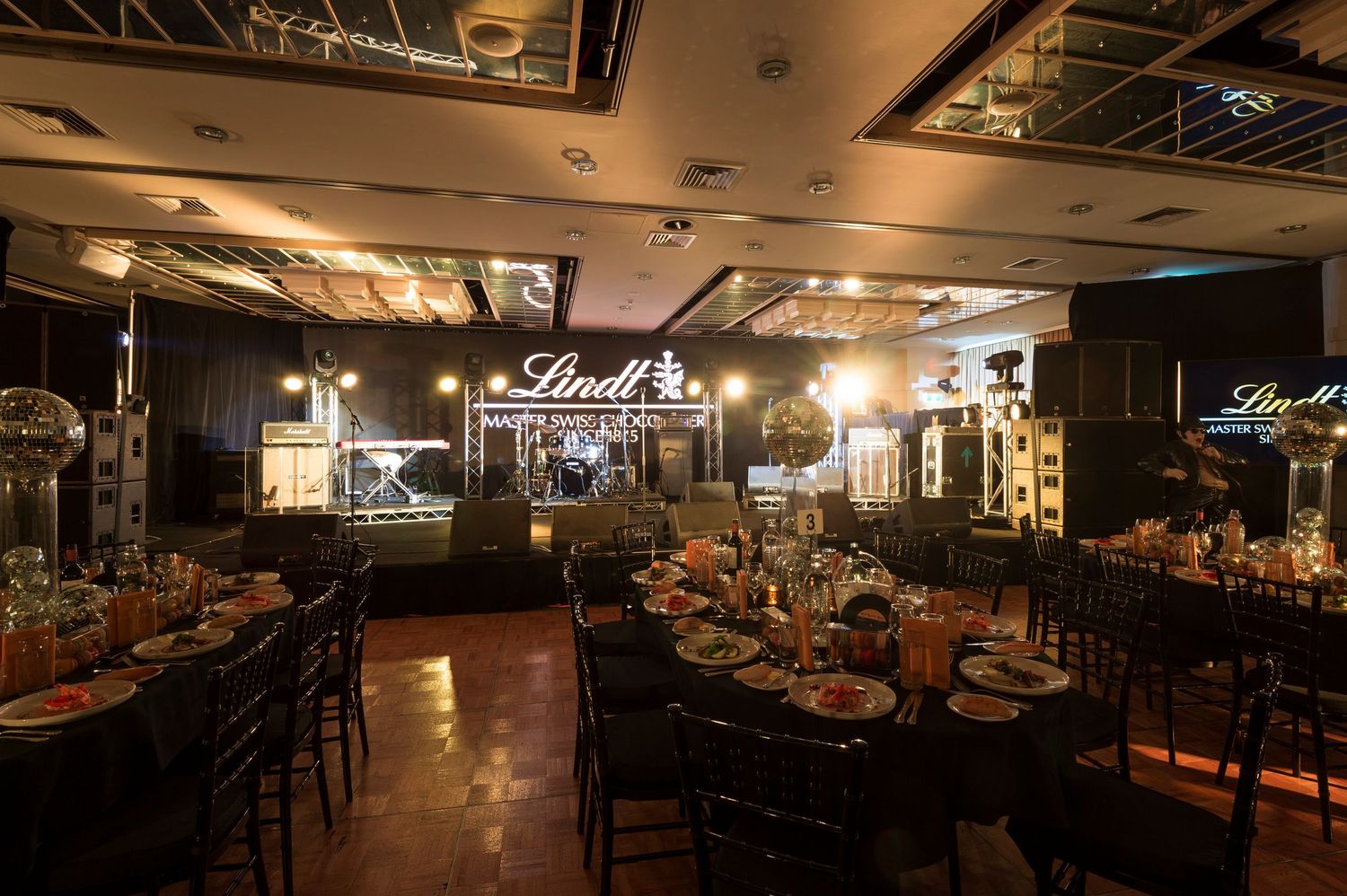 Dimly lit modern restaurant interior with warm lighting, exposed ceiling, and bar seating creates an intimate dining atmosphere.