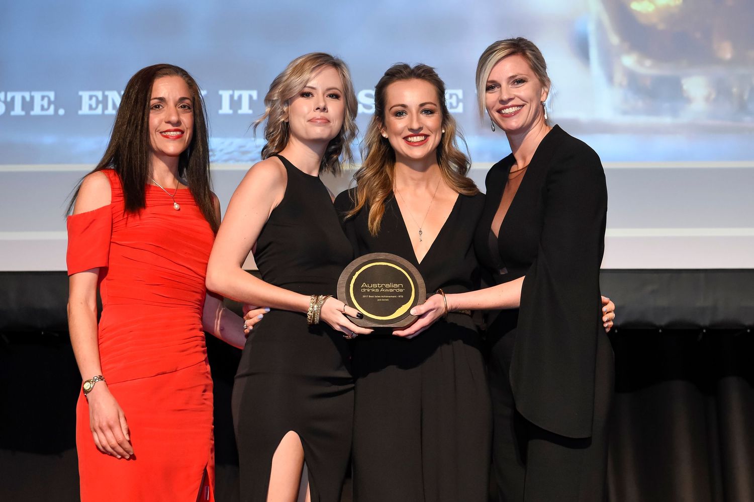 A group of people in formal attire stand together on stage holding an award during a ceremony.