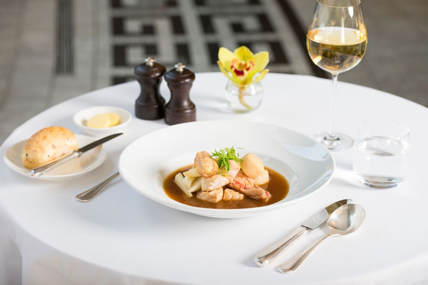 Elegant plated dessert with orange-colored elements and garnish on white plate in upscale restaurant setting.