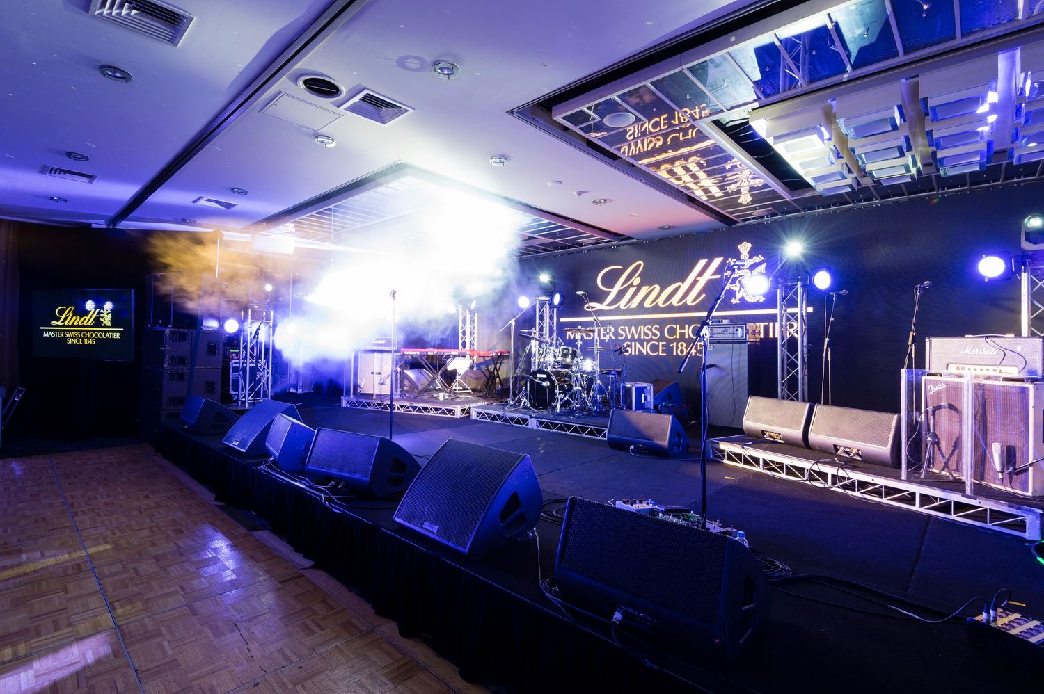 Empty concert stage with blue lighting and Lindt branding setup for a live music performance.