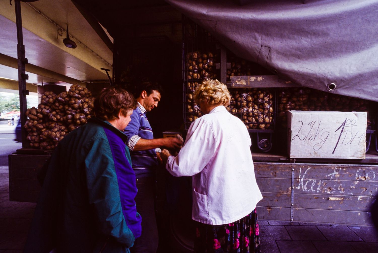 People gathered under tents near the Berlin Wall during nighttime.