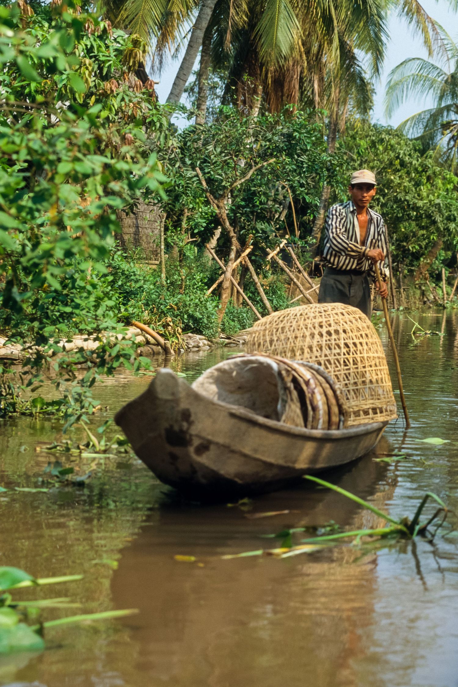 Traditional wooden boats with bamboo baskets navigate through palm-fringed waterways.