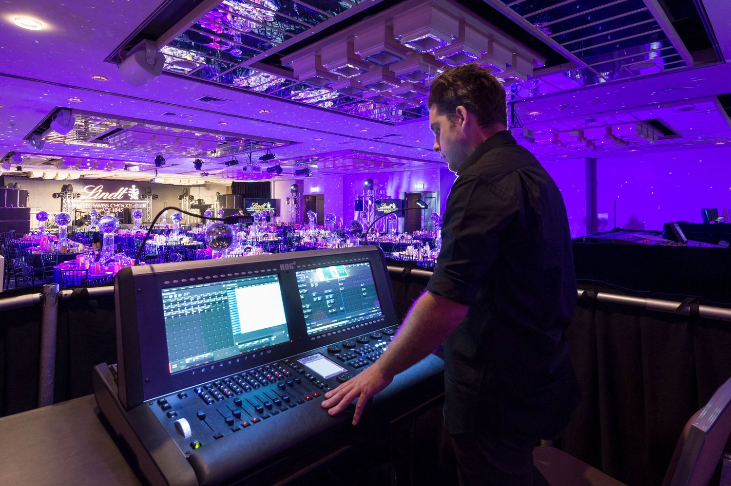 Wide angle view of recording studio control room illuminated with dramatic purple lighting.