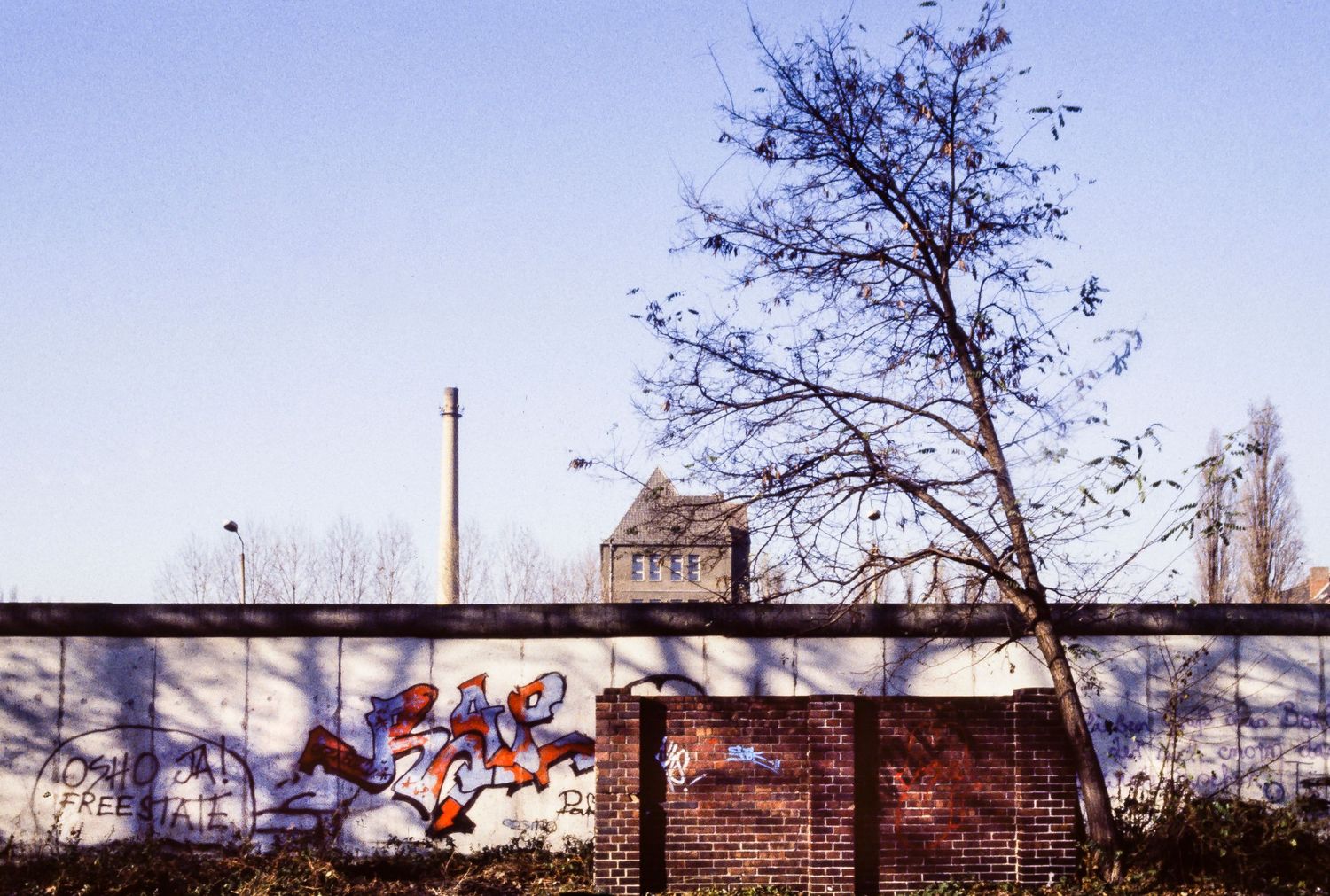 Panoramic view of the Berlin Wall stretching into the distance under a blue sky.