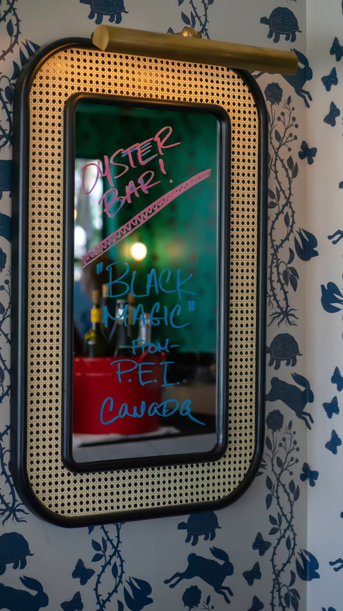 Oyster bar mirror sign advertising Black Magic oysters from PEI Canada on decorative wall.