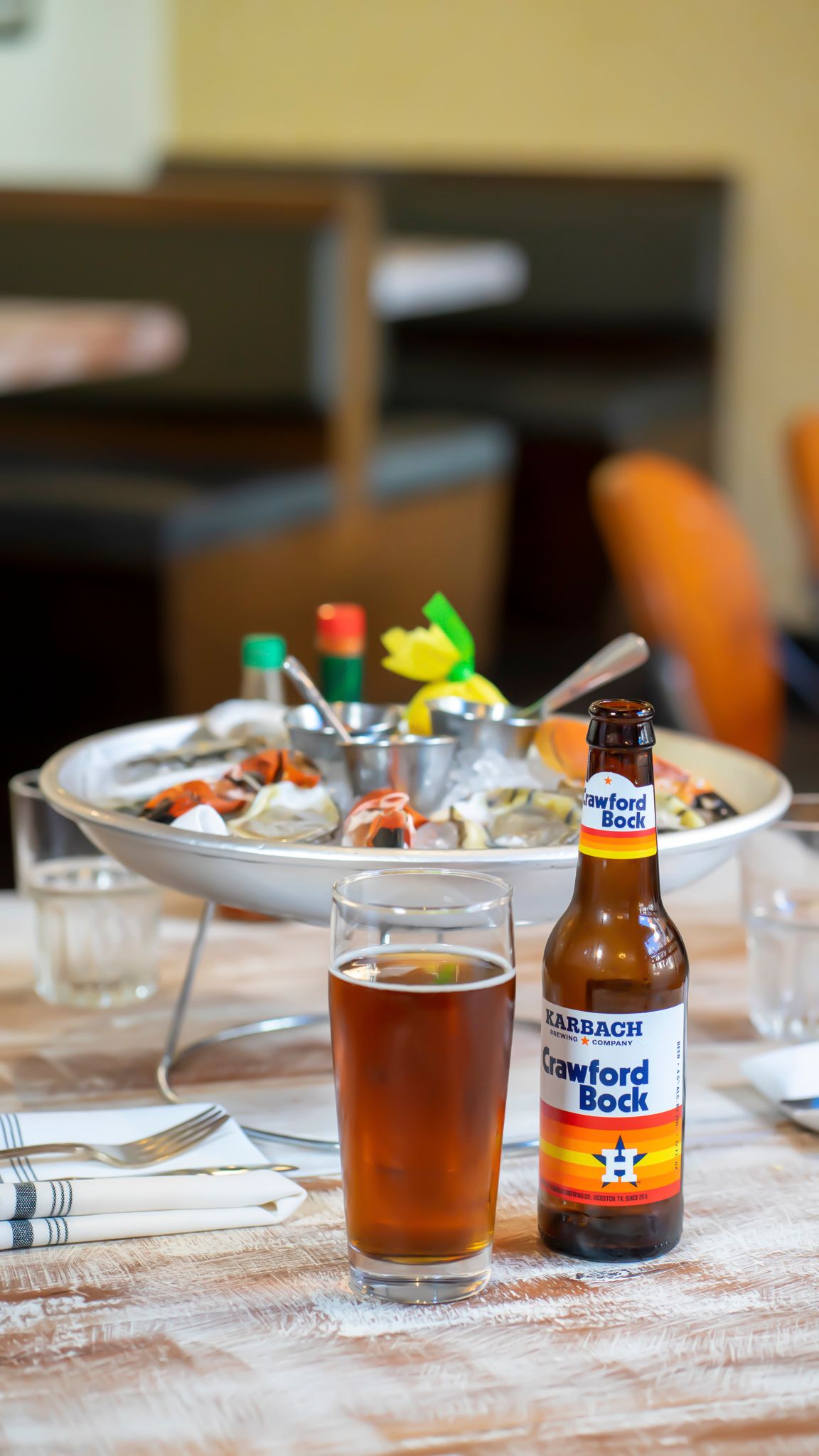 Karbach Crawford Bock beer bottle and glass beside a seafood platter on a restaurant table.