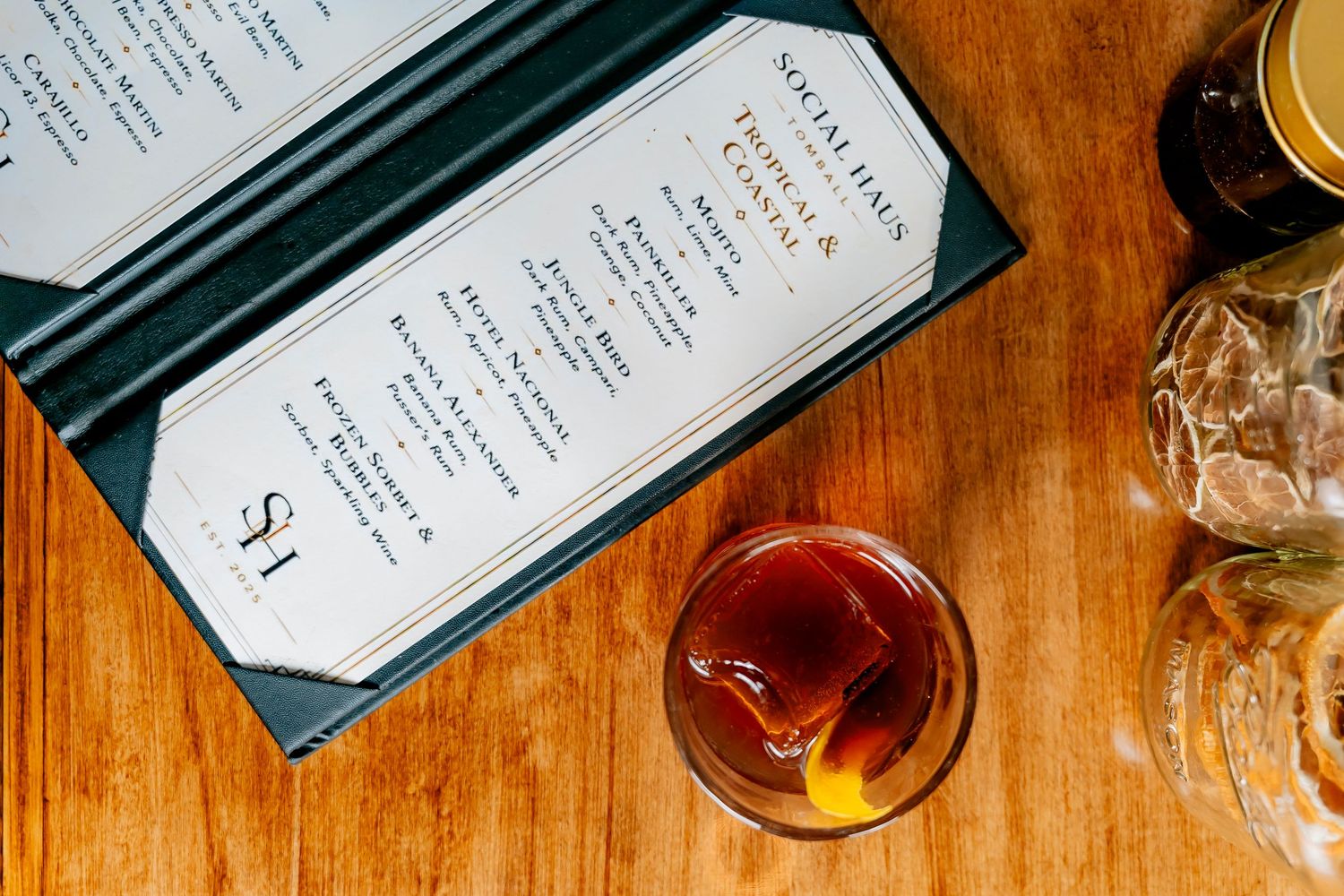 Cocktail menu and whiskey old fashioned drink on a wooden table at a upscale bar restaurant.